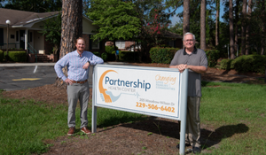David and John stand next to PHC sign